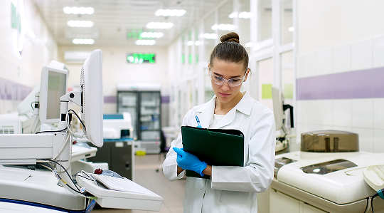 Quality control testing – laboratory technician with clipboard reviewing test data beside analytical instruments to verify product specifications